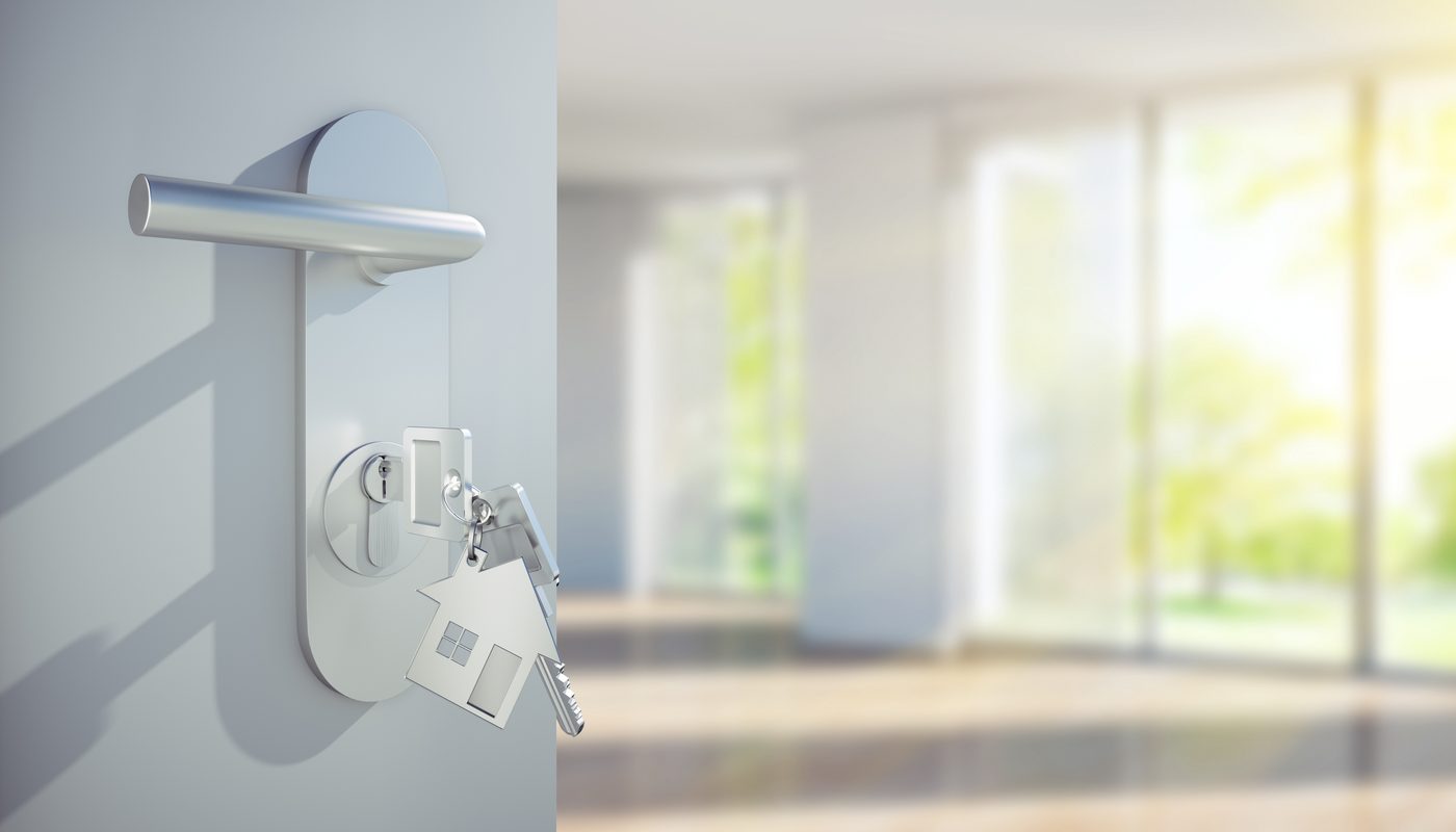 Wohnungstür mit steckendem Schlüssel, dahinter ein heller, leerer Wohnraum